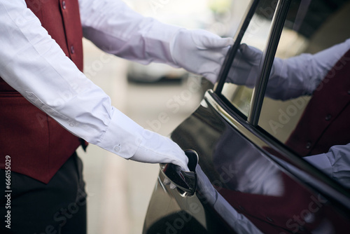 Close-up of doorman opening the door of the car and meeting the guest photo