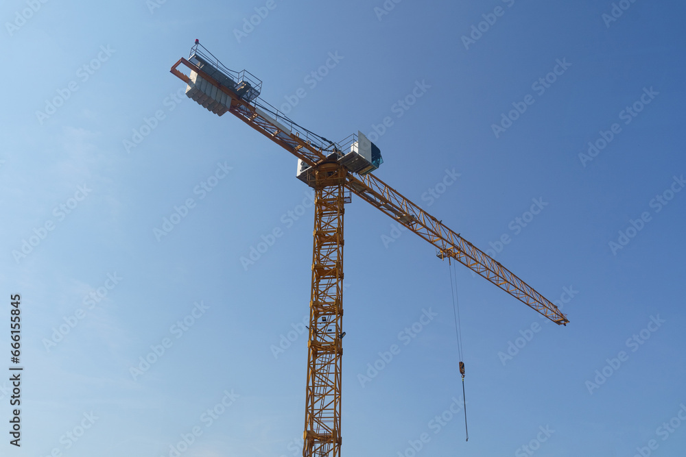Industrial crane on a construction site against a blue sky. Industrial crane on a construction site against a blue sky.