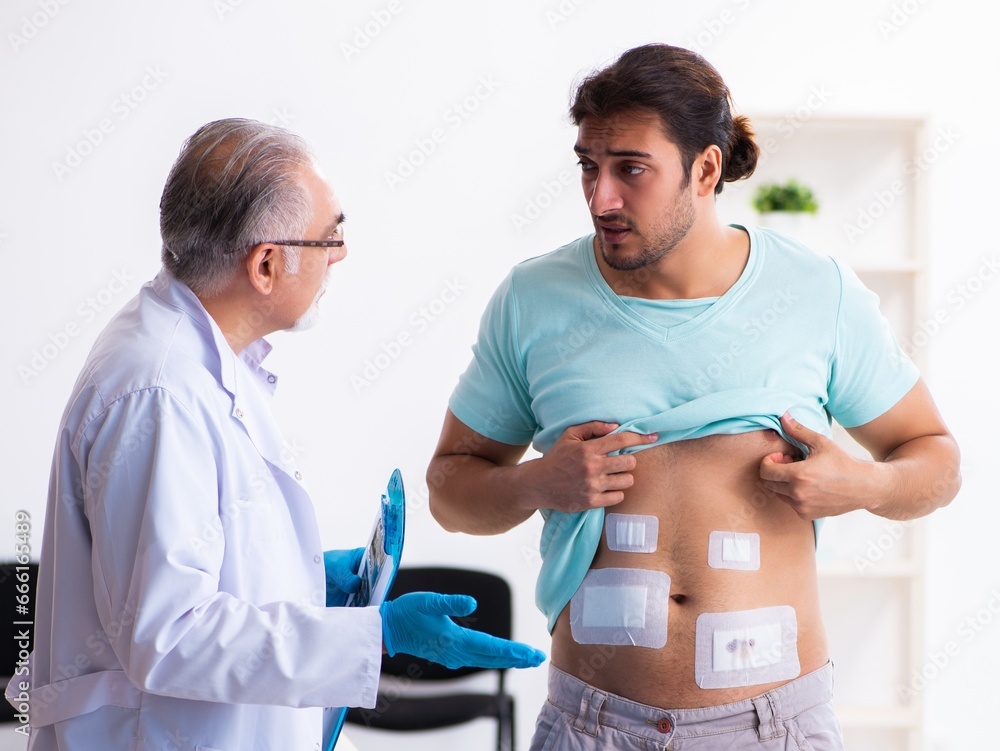 Injured young man visiting experienced male doctor Injured young man visiting experienced male doctor