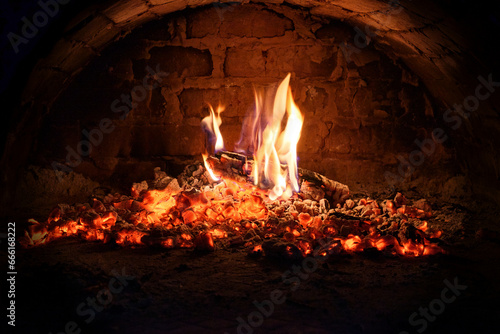 Logs of firewood burn out in the oven. Coals and flames in the fireplace.