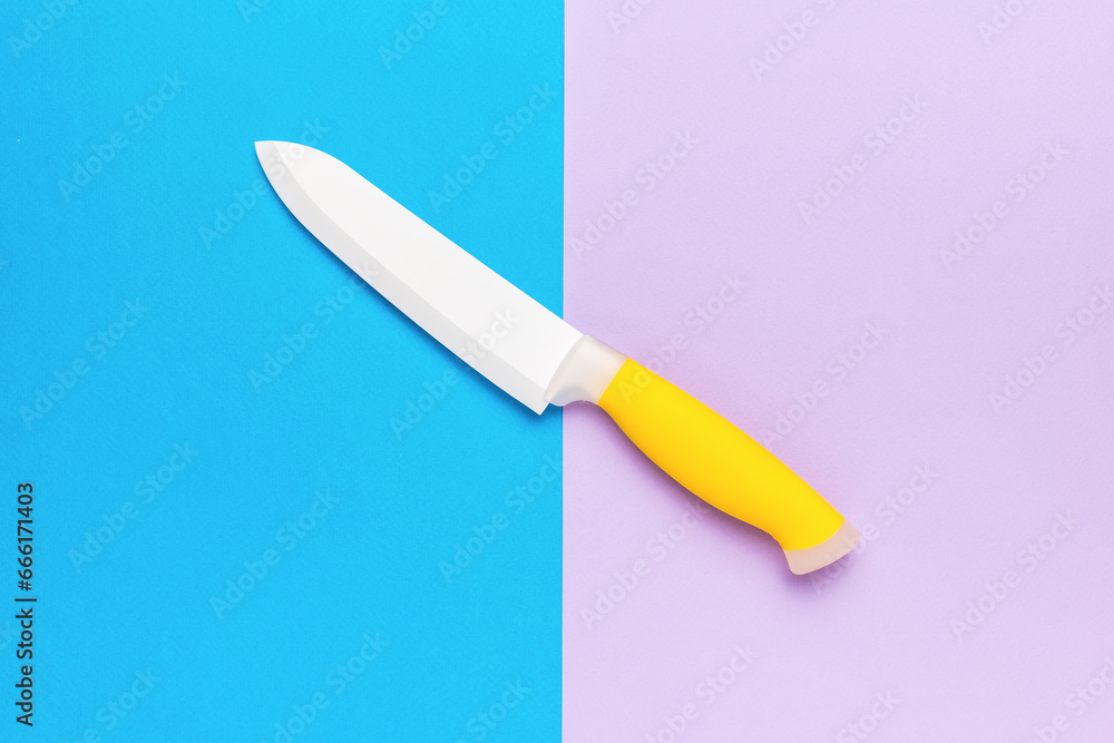 Ceramic white knife with a yellow handle on a violet-blue background. Accessory for cooking. Ceramic white knife with a yellow handle on a violet-blue background. Accessory for cooking.