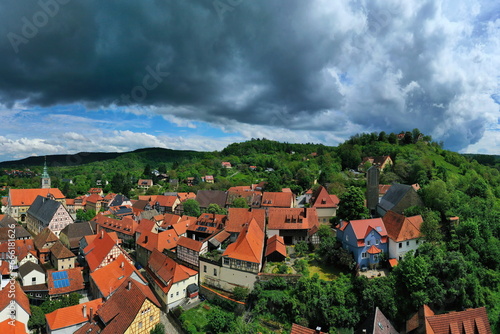 Luftbild von Königsberg in Bayern. Die Stadt ist von Hügeln und Wäldern umgeben. Der Himmel ist bewölkt und dunkel und deutet auf einen herannahenden Sturm hin.  photo