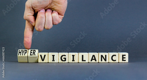 Vigilance or hypervigilance symbol. Concept words Vigilance Hypervigilance on wooden blocks. Beautiful grey background. Psychologist hand. Psychology vigilance hypervigilance concept. Copy space.