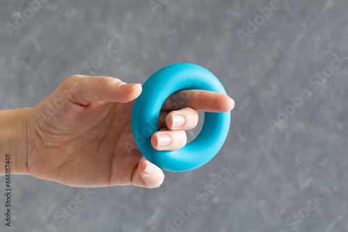 Woman trains hand holding a rubber expander to strengthen arms, the concept of strength and health.