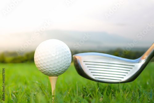 Golf ball set on tee and club head 1 mountain background.