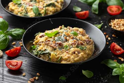 Creamy spaghetti squash pasta with parmesan cheese and sun dried tomato sauce served with pine nuts and basil.