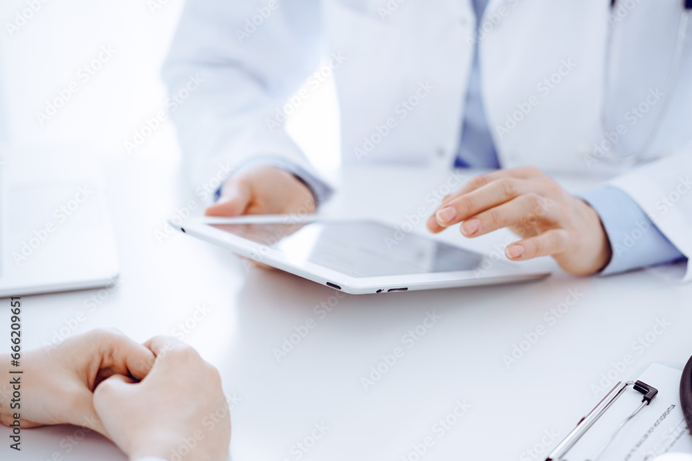 Stethoscope lying on the tablet computer in front of a doctor and patient sitting opposite each other and using tablet computer at the background . Medicine, healthcare concept Stethoscope lying on the tablet computer in front of a doctor and patient sitting opposite each other and using tablet computer at the background . Medicine, healthcare concept