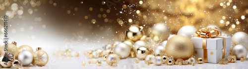 Christmas atmosphere, on a horizontal surface against a background of golden bokeh lie festive New Year decorations, balls and a gift around snow in white and gold tones. Christmas banner.