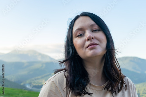 Portrait of a woman traveler standing against the background of mountains.