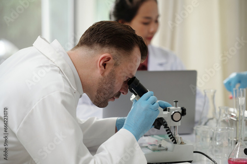 Scientist working in chemical laboratory focusing microscope before analyze samples