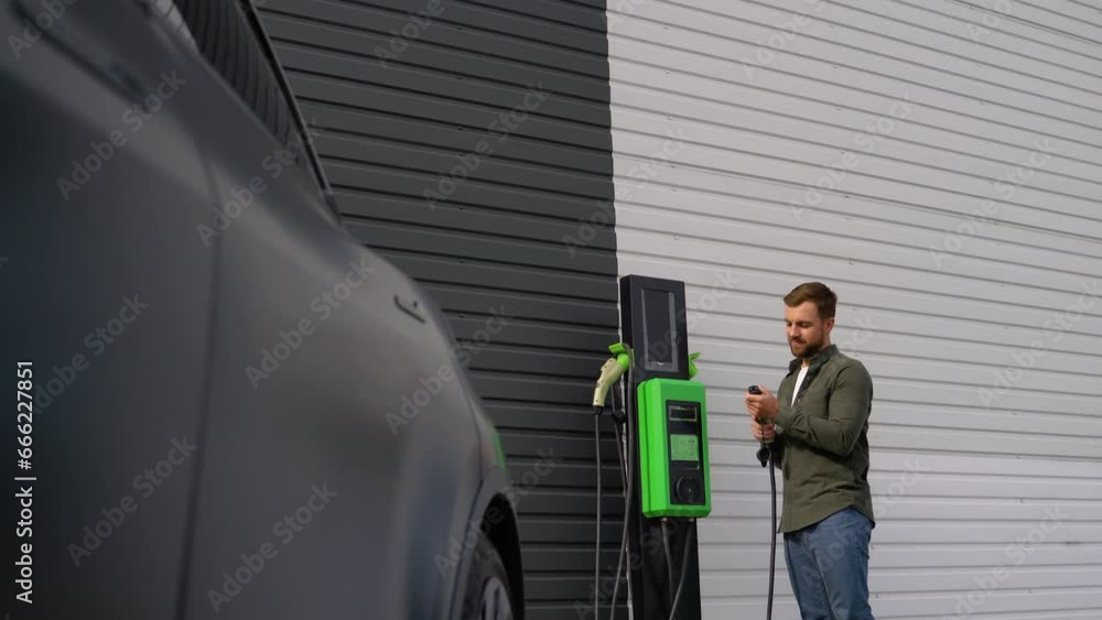 Man charging electric car by the house Man charging electric car by the house