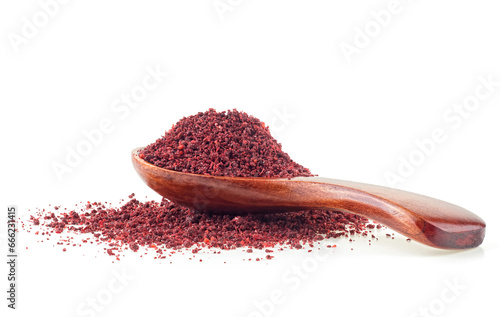 Wooden spoon on pile of sumac powder spice isolated on a white background photo