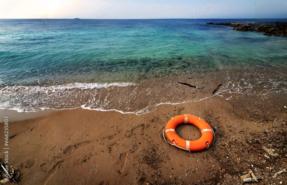 Obraz premium Mediterranean beach, abandoned on the beach an orange ring lifebuoy. Concept of emergency deaths at sea.