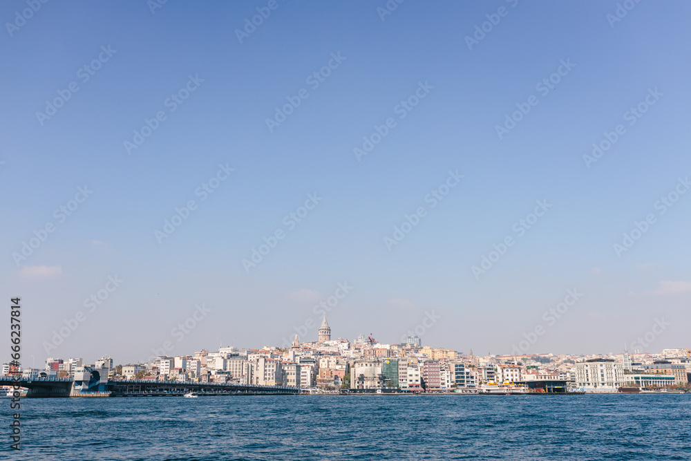 View of the Bosphorus skyline in Istanbul with historical buildings,Galata Tower and many cruise ships on a sunny day.Beautiful cityscape with sea and architecture. Istanbul, Türkiye - 15 October 2023