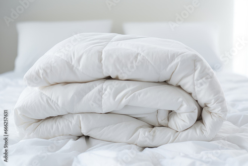 White folded duvet lying on white bed background. Preparing for winter season  household  domestic activities  hotel or home textile