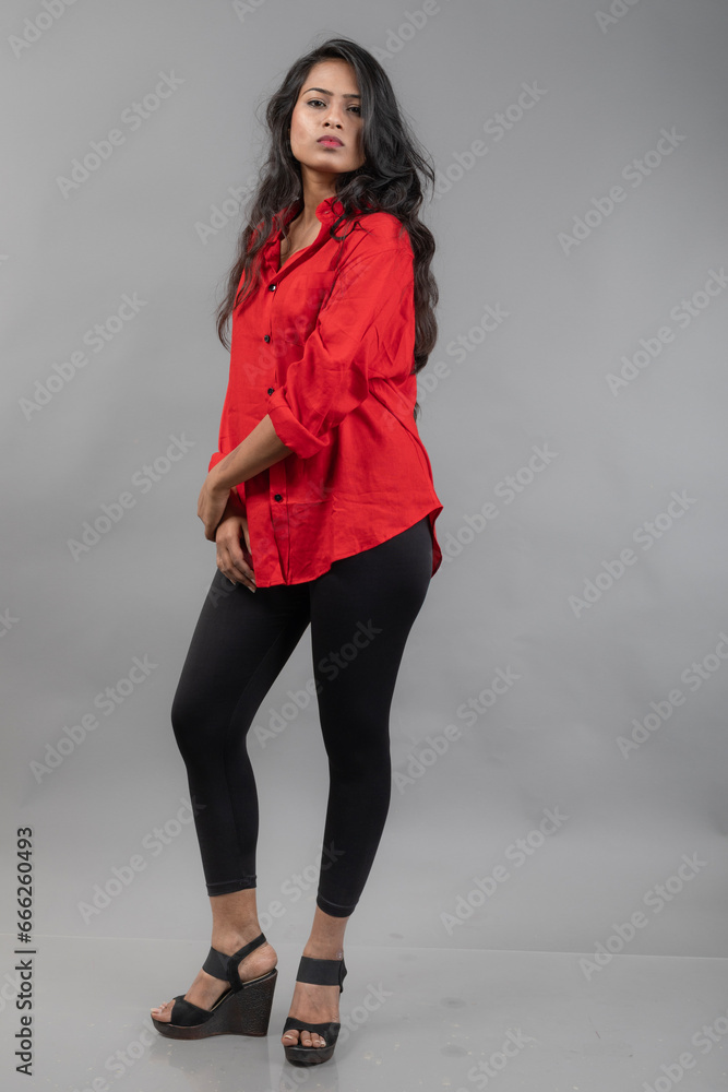 Indian young female model in casual wear against grey background - stock photo. Long black haired model wearing red shirt and black jeans. Indian young female model in casual wear against grey background - stock photo. Long black haired model wearing red shirt and black jeans.