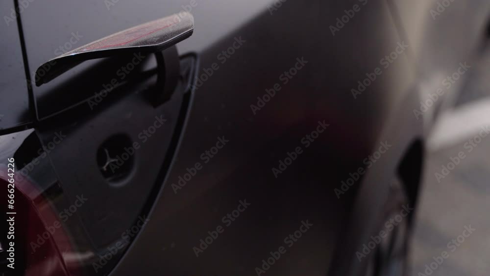 A man disconnects a charging cable to an electric car, close up A man disconnects a charging cable to an electric car, close up