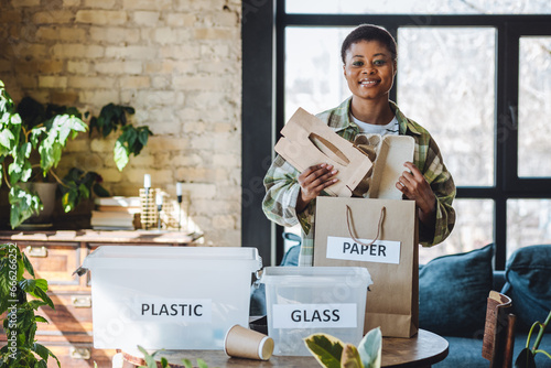 Young African American woman is doing garbage waste sorting at home. Concept of sustainable lifestyle, daily routine to protect planet from pollution, domestic life, simple actions for environment