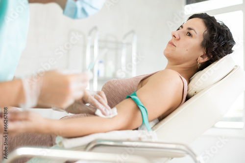 Cuadro en lienzo Middle-aged woman undergoing treatment by vein injection in light doctor's cabin