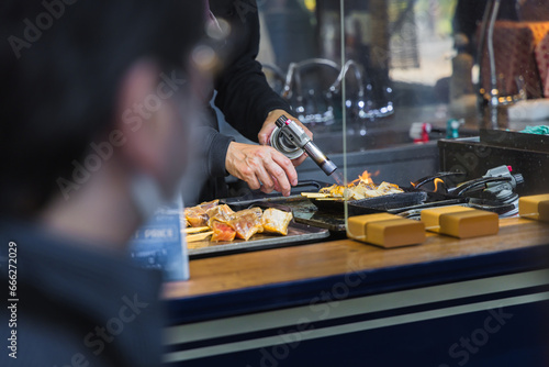 A chef at a street kitchen of the Tsukiji fish market in Tokyo preparing seafood using a Bunsen burner photo
