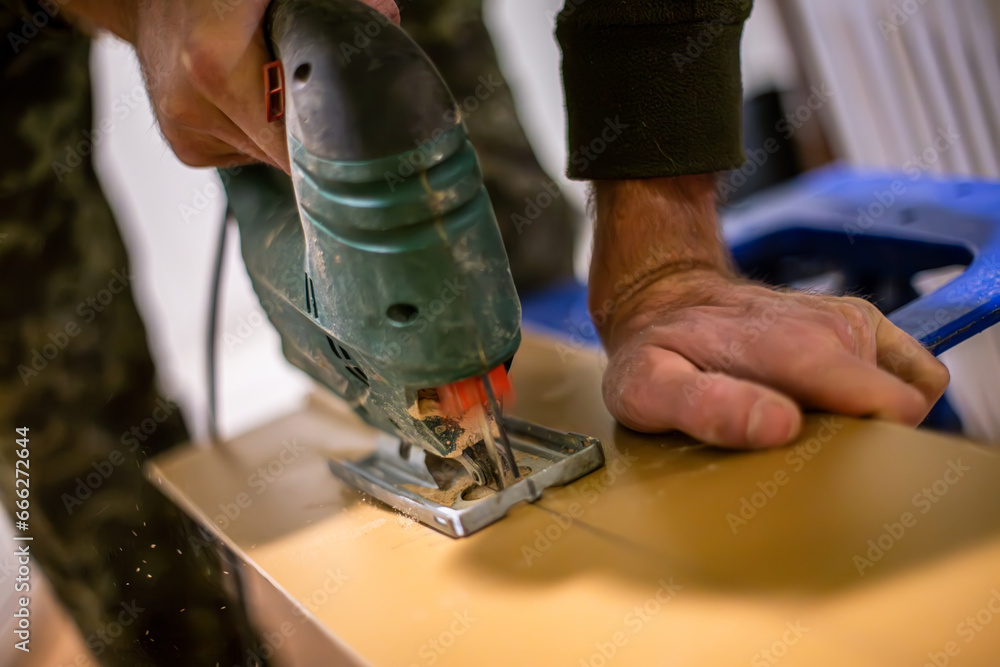 carpenter's hand using an electric jigsaw to cut wooden plywood. The plywood is cut into a precise shape, and the carpenter's hand is steady and confident. carpenter's hand using an electric jigsaw to cut wooden plywood. The plywood is cut into a precise shape, and the carpenter's hand is steady and confident.