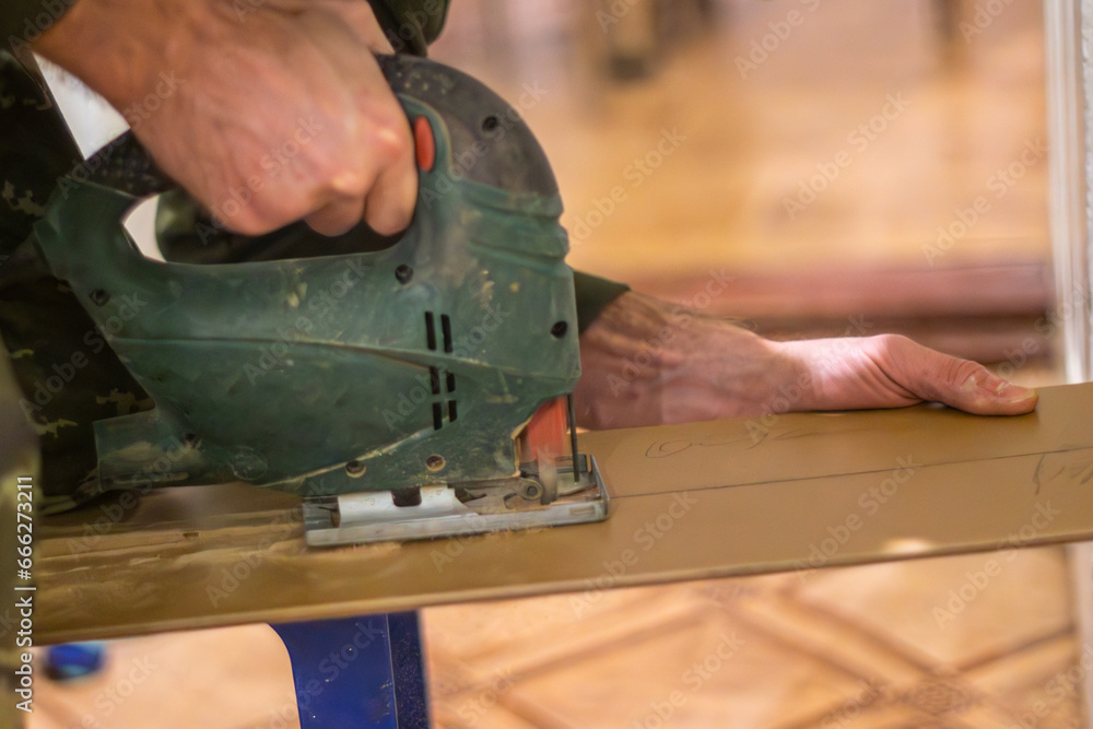 carpenter using an electric jigsaw to create a new piece of furniture from recycled materials. carpenter using an electric jigsaw to create a new piece of furniture from recycled materials.