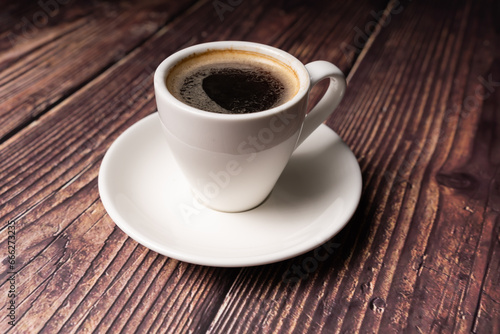 Close up of espresso coffee in white cup, on wooden table, vintage color tone, 