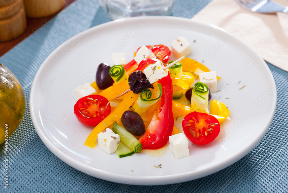 Plate of tasty Greek salad with fresh cucumbers, tomatoes, bell pepper and feta cheese