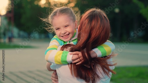 Photographie Child, daughter runs to mom hugs her in park on street in autumn