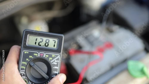 diagnostics of the car battery with a multimeter, voltage measurement on the contacts. photo