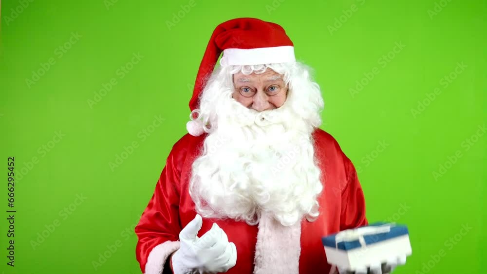 Cheerful authentic Santa points with finger someone shows and gives gift in box. Cheerful authentic Santa points with finger someone shows and gives gift in box.