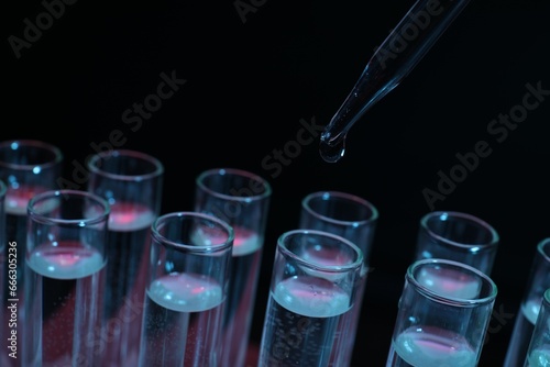 Dripping reagent into test tube on black background, closeup. Laboratory analysis