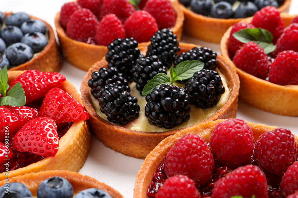 Tartlets with different fresh berries on white table, closeup. Delicious dessert Tartlets with different fresh berries on white table, closeup. Delicious dessert