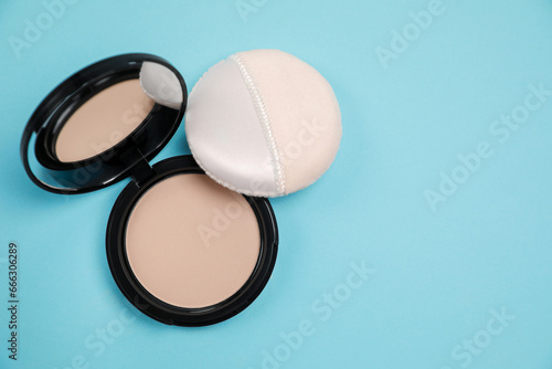 Face powder and puff on light blue background, flat lay. Space for text