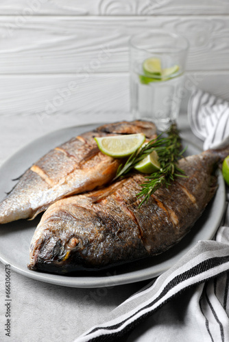 Delicious baked fish with rosemary and lime on grey table. Seafood