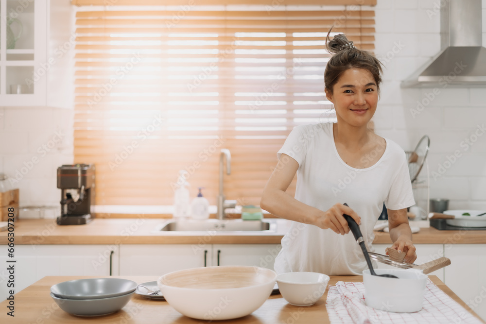 Happy asian woman serving soup into the small bowl. Happy asian woman serving soup into the small bowl.