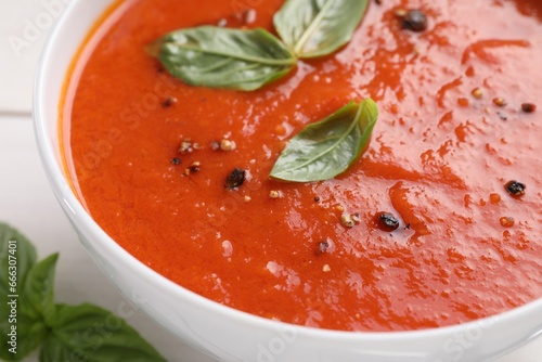 Delicious tomato cream soup in bowl on white table, closeup