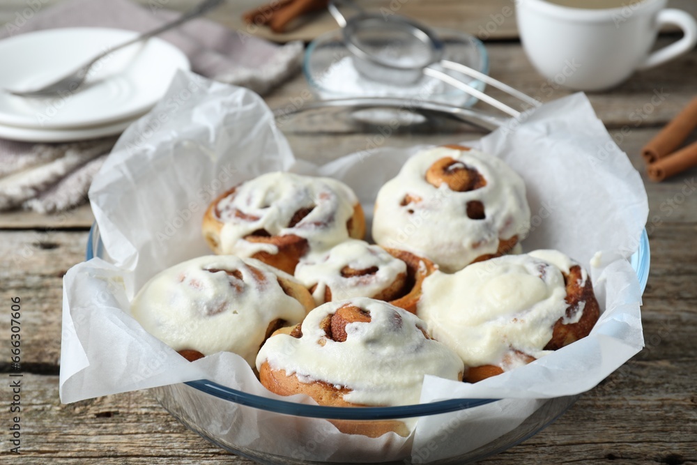Tasty cinnamon rolls with cream on wooden table, closeup Tasty cinnamon rolls with cream on wooden table, closeup
