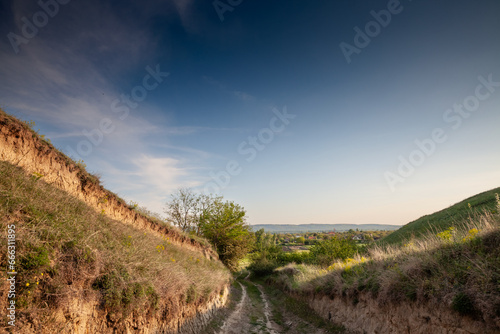 Panorama of Titelski breg, or titel hill, in Vojvodina, Serbia, with a dirtpath countryside road, in an agricultural landscape ay dusk on sunny sky.