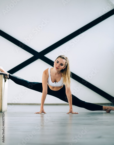Joyful confident adult athlete stretching legs in sport club