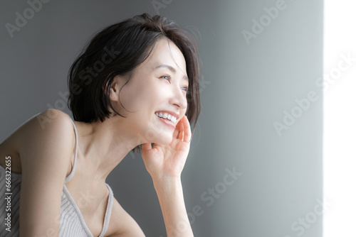 Fotografia 窓際を笑顔で見つめる女性のクローズアップの横顔　美容やポシティブなイメージに
