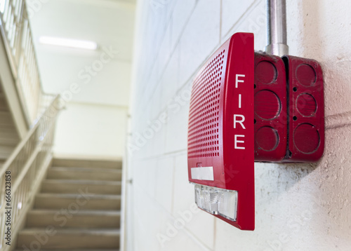 red, wall-mounted fire alarm with a glowing indicator, ready to alert in emergencies, symbolizing safety and preparedness photo