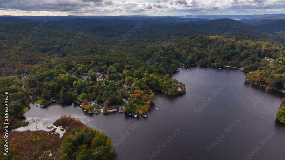 A high altitude view over Oscawana Lake in NY during the fall season on a cloudy day. The drone camera dolly in then tilt down over the quiet and peaceful lake scenery. A high altitude view over Oscawana Lake in NY during the fall season on a cloudy day. The drone camera dolly in then tilt down over the quiet and peaceful lake scenery.
