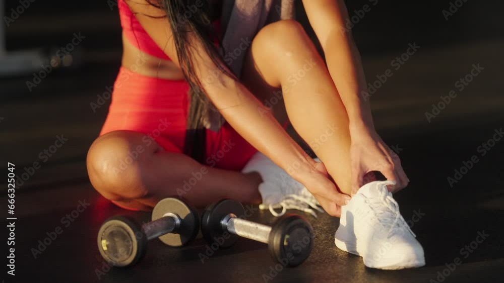 Young asian woman massaging painful ankle after sport injury at the gym