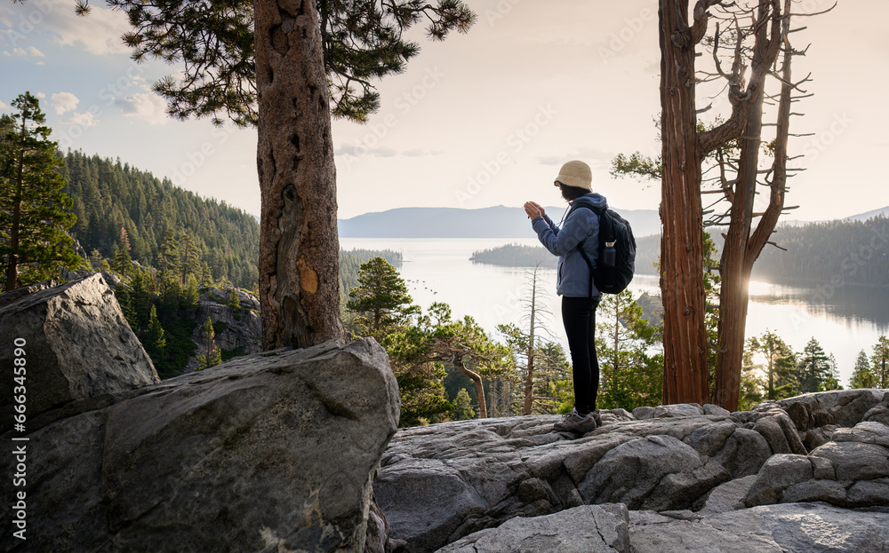 Obraz premium Woman taking videos using smartphone at Emerald Bay. South Lake Tahoe at sunrise. California.