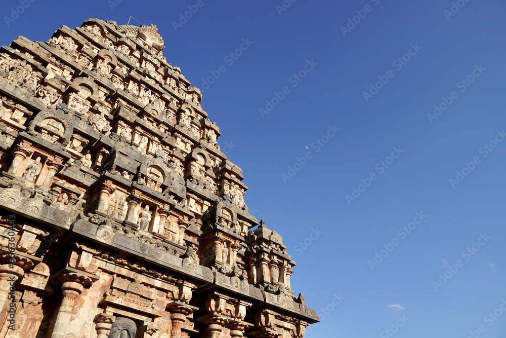 Tower of Airavatesvara Temple, Darasuram, Kumbakonam, Tamilnadu. Ancient hindu temple tower with carvings of God sculpture isolated against blue sky background in Tamilnadu.