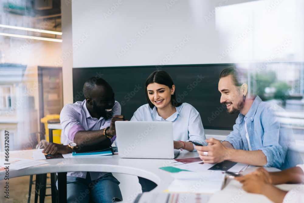 Multiethnic workers discussing ideas and smiling in light office Multiethnic workers discussing ideas and smiling in light office
