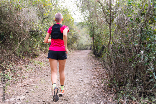 rear view of a woman practicing trail running in the forest, concept of sport in nature and healthy lifestyle, copy space for text