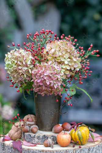 Blumenstrau   mit Hortensienbl  ten und Hagebutten in einem vintage Kupferbecher im Garten
