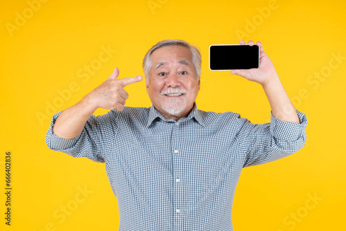 Asian senior man , old man feel happy good health , Excited surprised face showing smart phone with blank screen , black screen isolated on yellow background , Mock Up Image